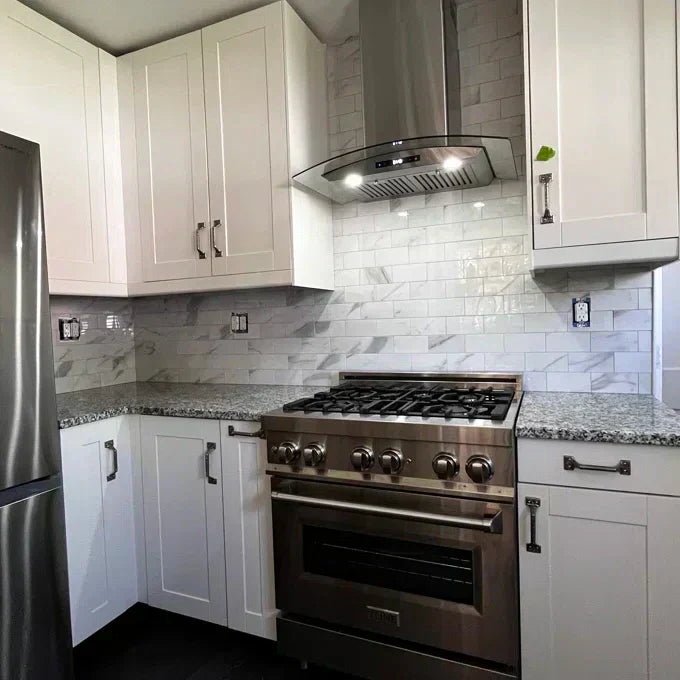 Carrara White peel and stick backsplash in modern kitchen with stainless steel appliances and white cabinets.