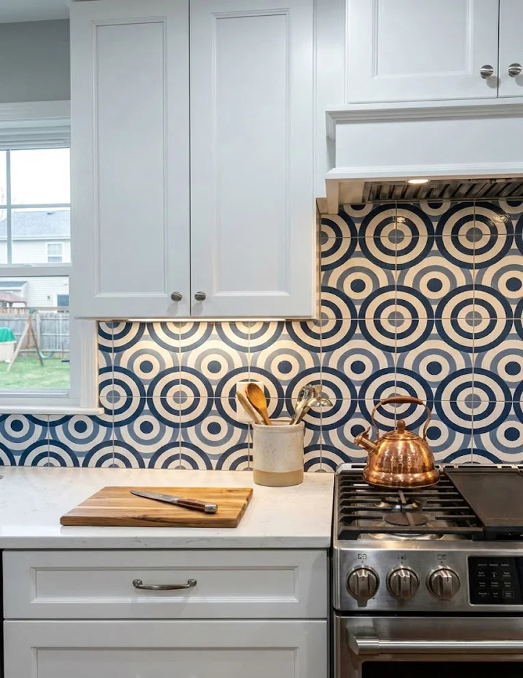 A renovated kitchen featuring Colamo Blue Ring glossy peel and stick backsplash, reflecting under-cabinet lighting behind a copper kettle.